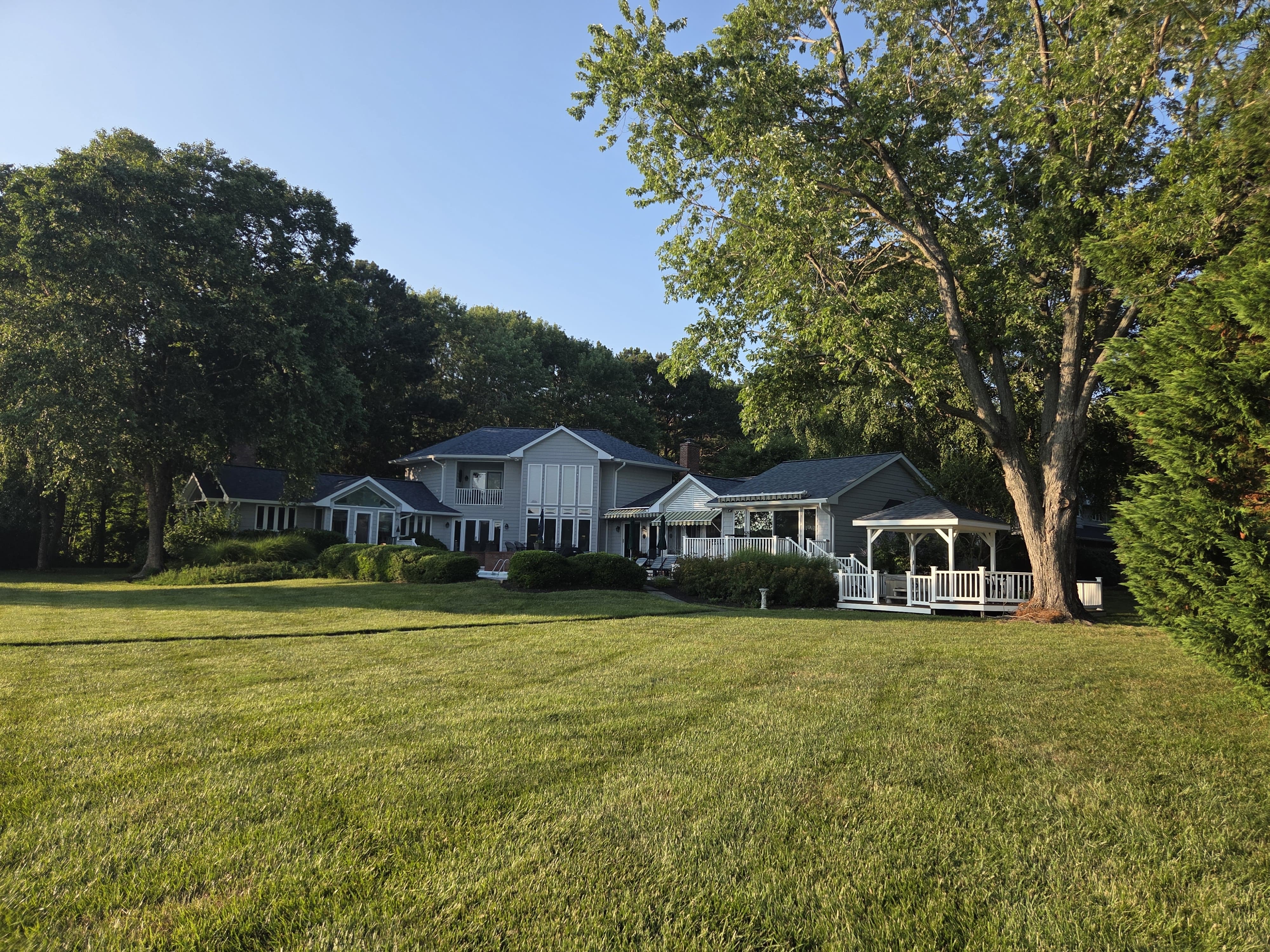 Rear elevation of a large waterfront home showing completed roofing work across multiple sections